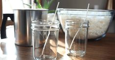 two mason jars with straws are sitting on a table in front of a pot