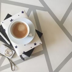 a cup of coffee sitting on top of a stack of books next to a camera