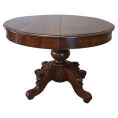 a round wooden table with two leaves on it