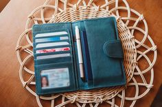 an open wallet sitting on top of a wicker table next to a pen and pencil