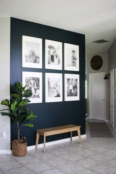 a living room with pictures hanging on the wall and a bench in front of it