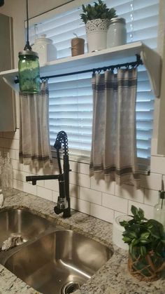 a kitchen sink under a window next to a potted plant