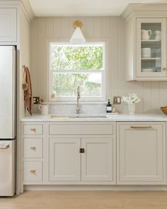 a kitchen with white cabinets and an open window above the sink is seen in this image