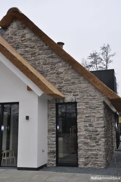 a small white building with a thatched roof and black glass doors on the front