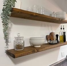 two wooden shelves filled with glassware and other items next to each other on the wall