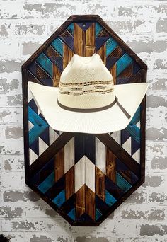 a white hat hanging on the wall next to a wooden hexagonal frame with blue and brown designs