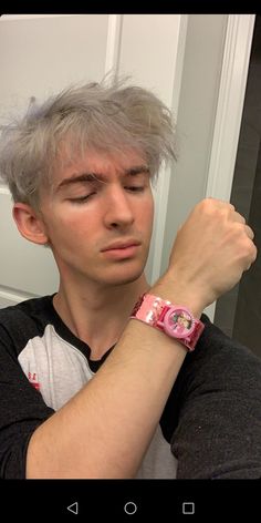 a young man with grey hair wearing a pink watch