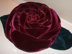 a large red rose sitting on top of a white table next to a green cloth