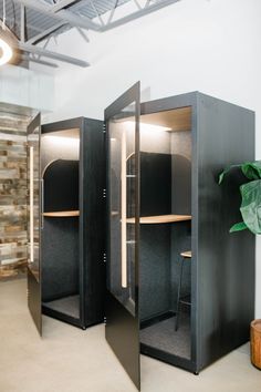 an office cubicle with two open doors and a potted plant in the corner