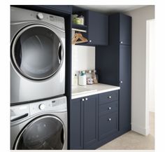 a washer and dryer in a laundry room with blue cabinets, white counter tops