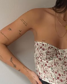 a woman with tattoos on her arm and chest is standing in front of a wall