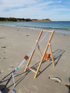 a hammock stand on the beach with an orange shirt hanging from it's side