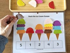 a child's hand is holding an ice cream scoops game