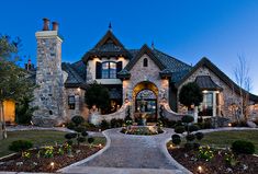 a large house that is lit up at night with lights on the front and side