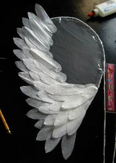 an angel wing is sitting on top of a desk next to some pens and pencils