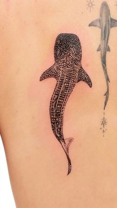 a woman with a tattoo on her back has a shark and a dolphin in it