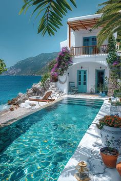 an outdoor swimming pool next to a house with flowers and potted plants on the side