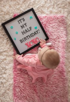 a baby is laying on the floor next to a sign that says it's my may birthday