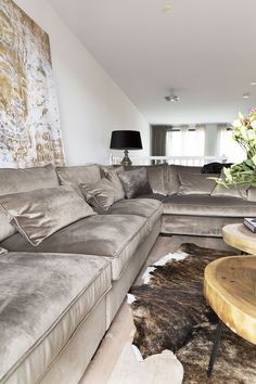 a living room with couches and a table in front of a large painting on the wall