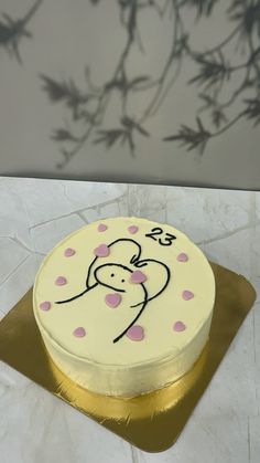 a white cake with pink polka dots and a monkey on it sitting on a gold plate