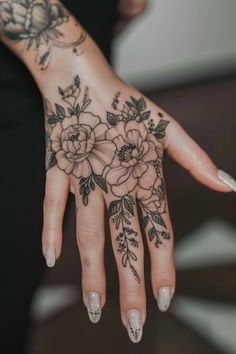 Hand adorned with intricate floral tattoos and manicured nails. Women’s Hands Tattoo, Witchy Finger Tattoo Ideas, Tattoo Ideas On Hand For Women, Wrist Into Hand Tattoo, Girly Finger Tattoos Pretty, Cute Finger Tattoos With Meaning, Front Of Hand Tattoo, Small Simple Finger Tattoos, Women's Hand Tattoos