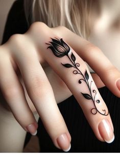 a woman's hand with a black flower tattoo on her left thumb and finger