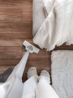 a close up of a person vacuuming the floor next to a bed with white blankets