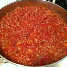 a large pot filled with lots of red sauce on top of a stove burner