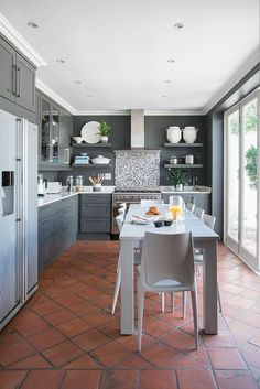 a kitchen with grey cabinets and tile flooring next to a white refrigerator freezer