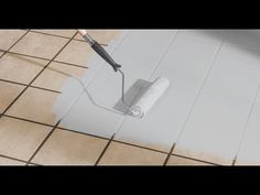 a person using a roller to paint a tile floor