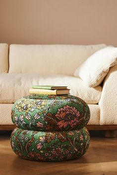 a green ottoman sitting on top of a hard wood floor next to a white couch