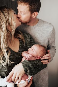 a man and woman kissing their newborn baby