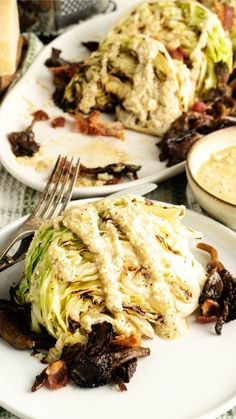 two white plates with food on them sitting on a green table cloth next to silverware