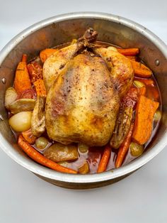 a cooked chicken in a pot with carrots and potatoes