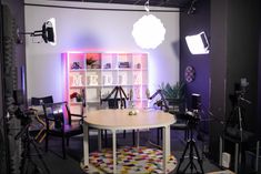 a camera set up in front of a table with chairs and lights on the wall