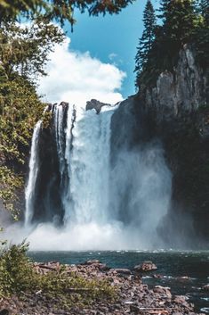 a large waterfall with water pouring out of it's sides and trees around it