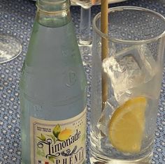 a bottle of lemonade next to a glass filled with ice