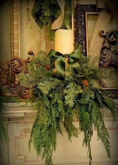 a candle is sitting on a mantle decorated with greenery