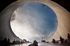 a group of people sitting on the ground in front of a large circular object that looks like a fish eye lens