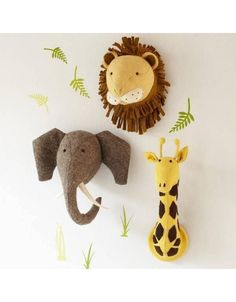 two stuffed animals and one giraffe are hanging on the wall next to each other