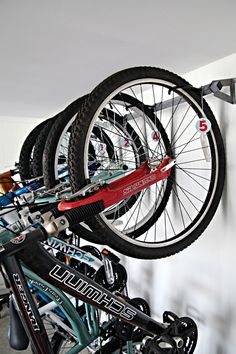 there are many bikes hanging on the wall in this bike storage area, and one is upside down