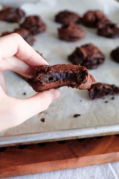 someone is holding a chocolate cookie in their hand and it looks like they are about to be eaten