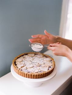 a person reaching for a dessert on top of a white cake plate with a bowl of oatmeal in it