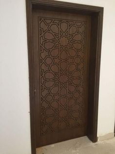 a wooden door with an intricate design on the front and side panels, in a white walled room