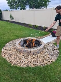 a man is pulling something out of the fire pit with a rope and water bottle