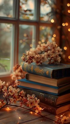 three books are stacked on top of each other in front of a window with christmas lights