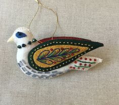 a white bird ornament hanging from a string on a gray cloth covered surface