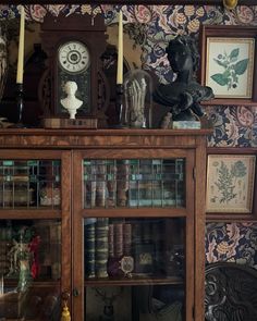 an old bookcase with many books and other items on top of it in front of a wallpapered wall