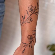 a woman's arm with flowers and leaves tattooed on the side of her leg