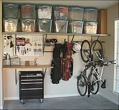 a garage with several storage bins on the wall and two bikes parked in front of it